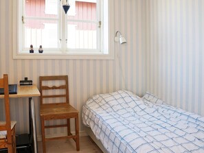 A room with a bed, a desk, a chair, a window, and a wall-mounted lamp. - Holiday Home in HÃ¤lleviksstrand (Hälleviksstrand)
