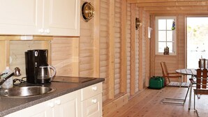 A kitchen with a coffee maker, sink, and cabinets. There is a dining area with a table and chairs. - Holiday Home in HÃ¤lleviksstrand (Hälleviksstrand)