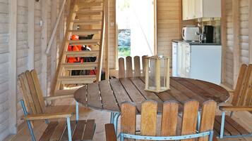 A wooden interior with a round table and chairs, a staircase, and a kitchen area.