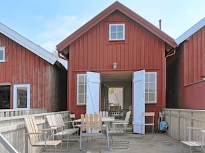A red barn with a porch, wooden chairs, and tables.