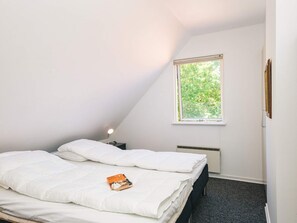 A bedroom with a bed, a bedside table, a window, and a radiator. - 4 Star Holiday Home in Haderslev (Haderslev)