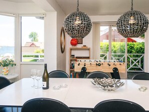 A dining area with a table, chairs, a wine bottle, glasses, a decorative bowl, and a foosball table. - 4 Star Holiday Home in Haderslev (Haderslev)