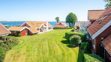 A residential area with multiple houses, a well-maintained lawn, and a view of the sea.