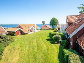 A residential area with multiple houses, a well-maintained lawn, and a view of the sea. - 4 Star Holiday Home in Haderslev (Haderslev)