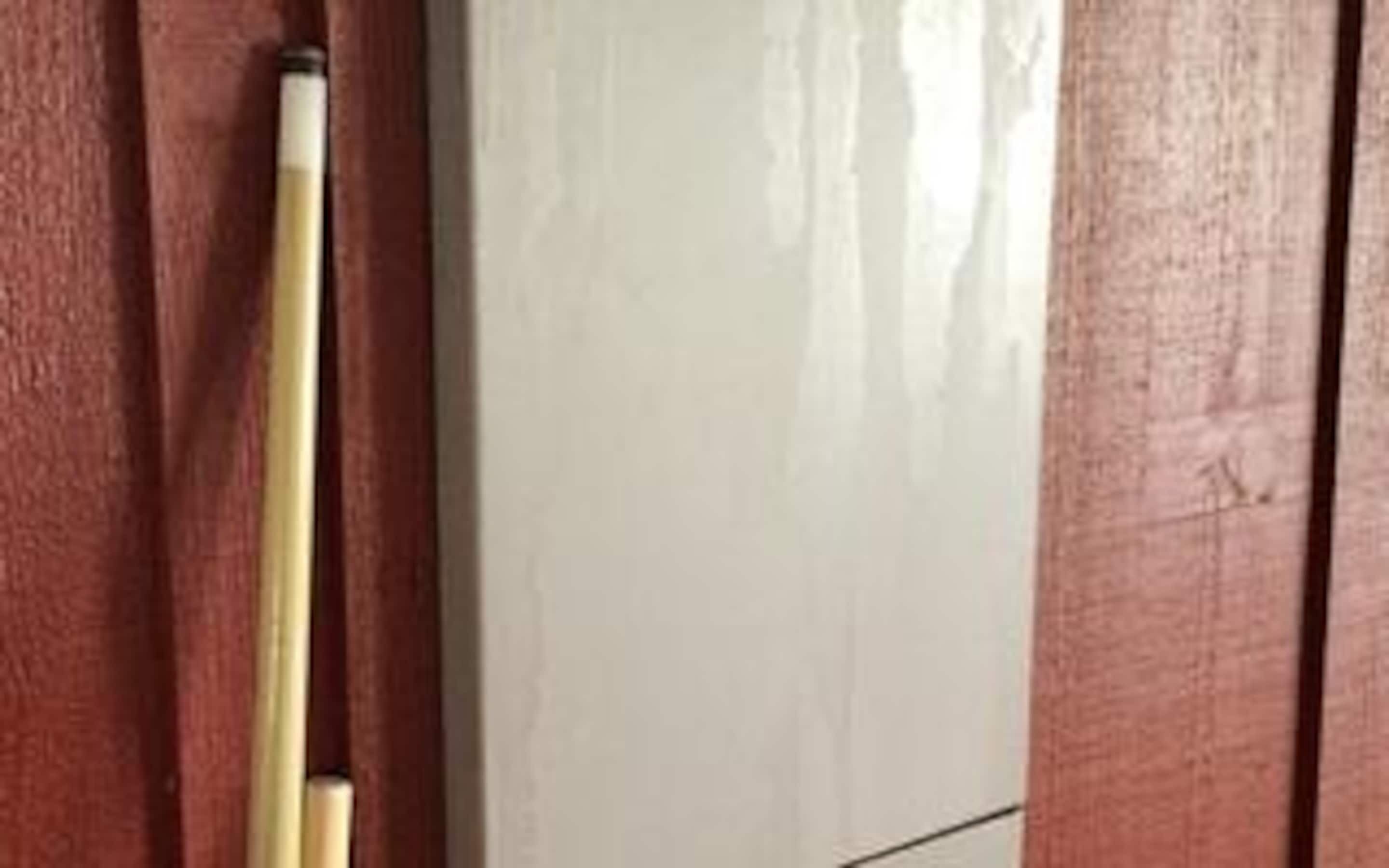 A wooden door with a white door handle and a visible reflection of a room.