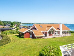 A coastal house with a large deck, a swimming pool, and a view of the sea.