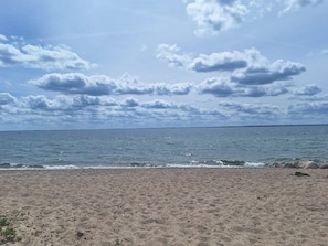 A beach with a sandy shore and a view of the sea under a partly cloudy sky.