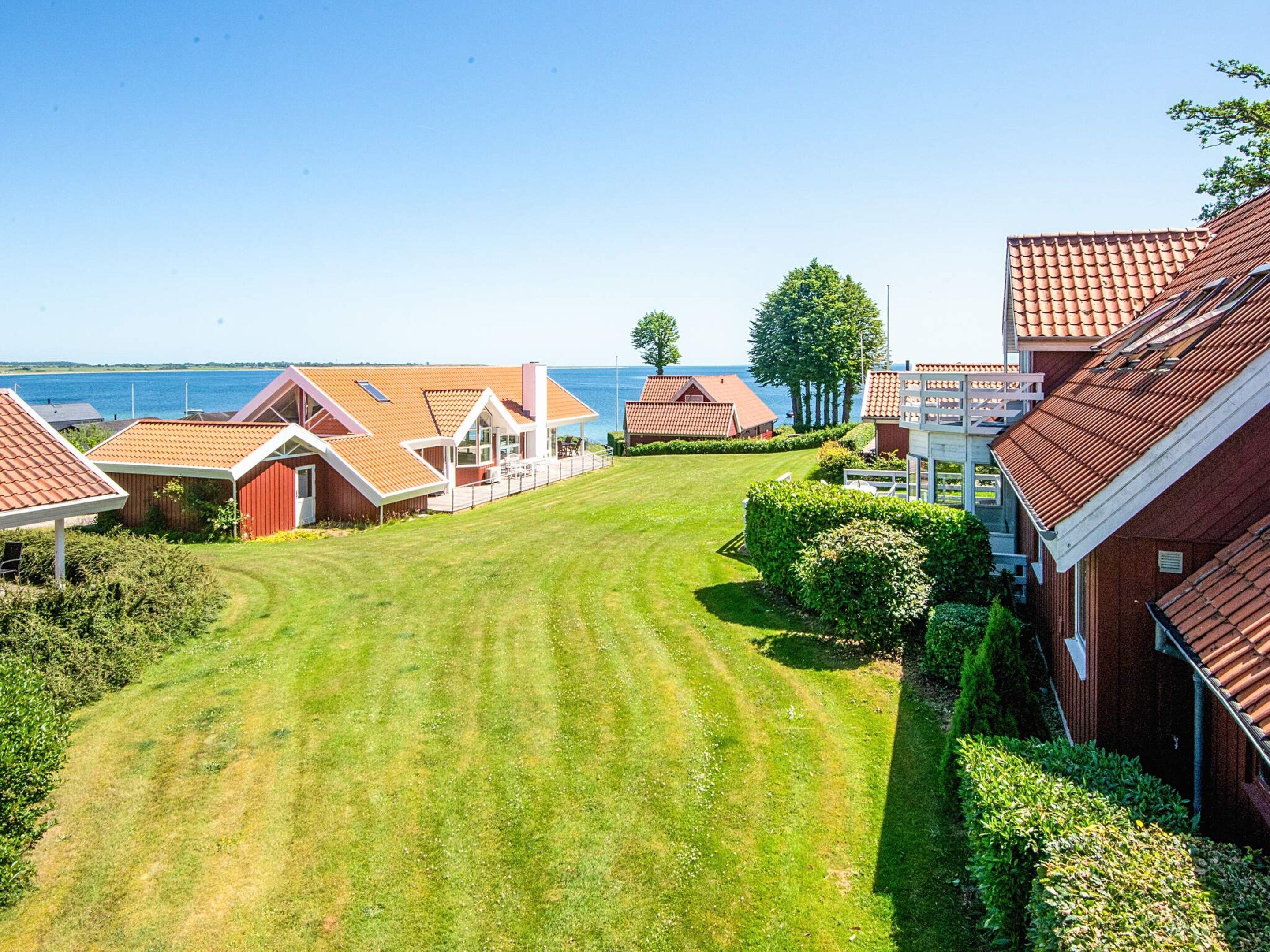 A residential area with houses, a grassy lawn, and a view of the sea.