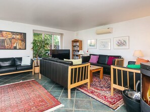 A living room with a sofa, a coffee table, a TV, a bookshelf, and a fireplace. - 4 Star Holiday Home in Haderslev (Haderslev)