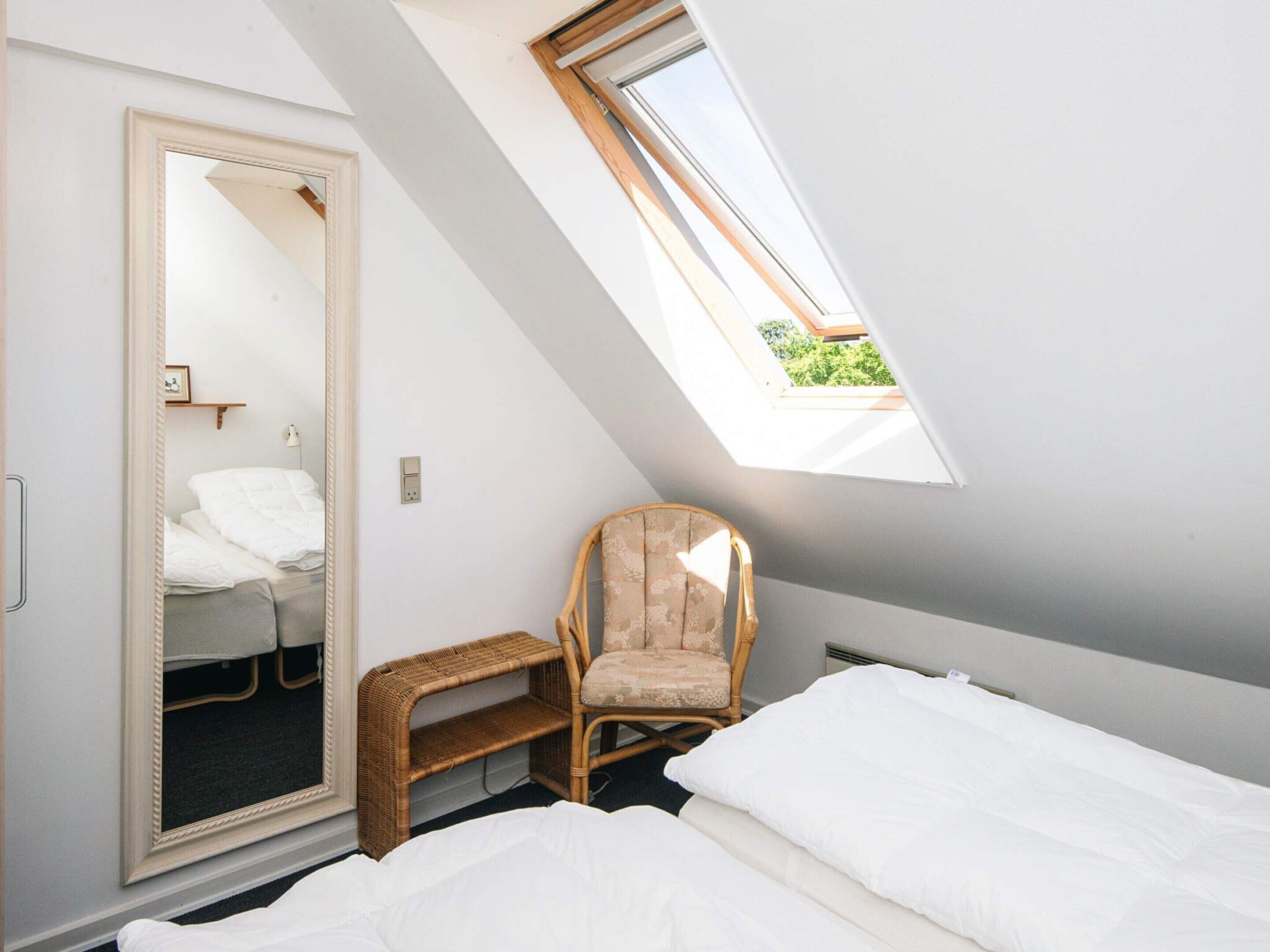 A bedroom with a skylight, a wardrobe, a chair, and a bed.