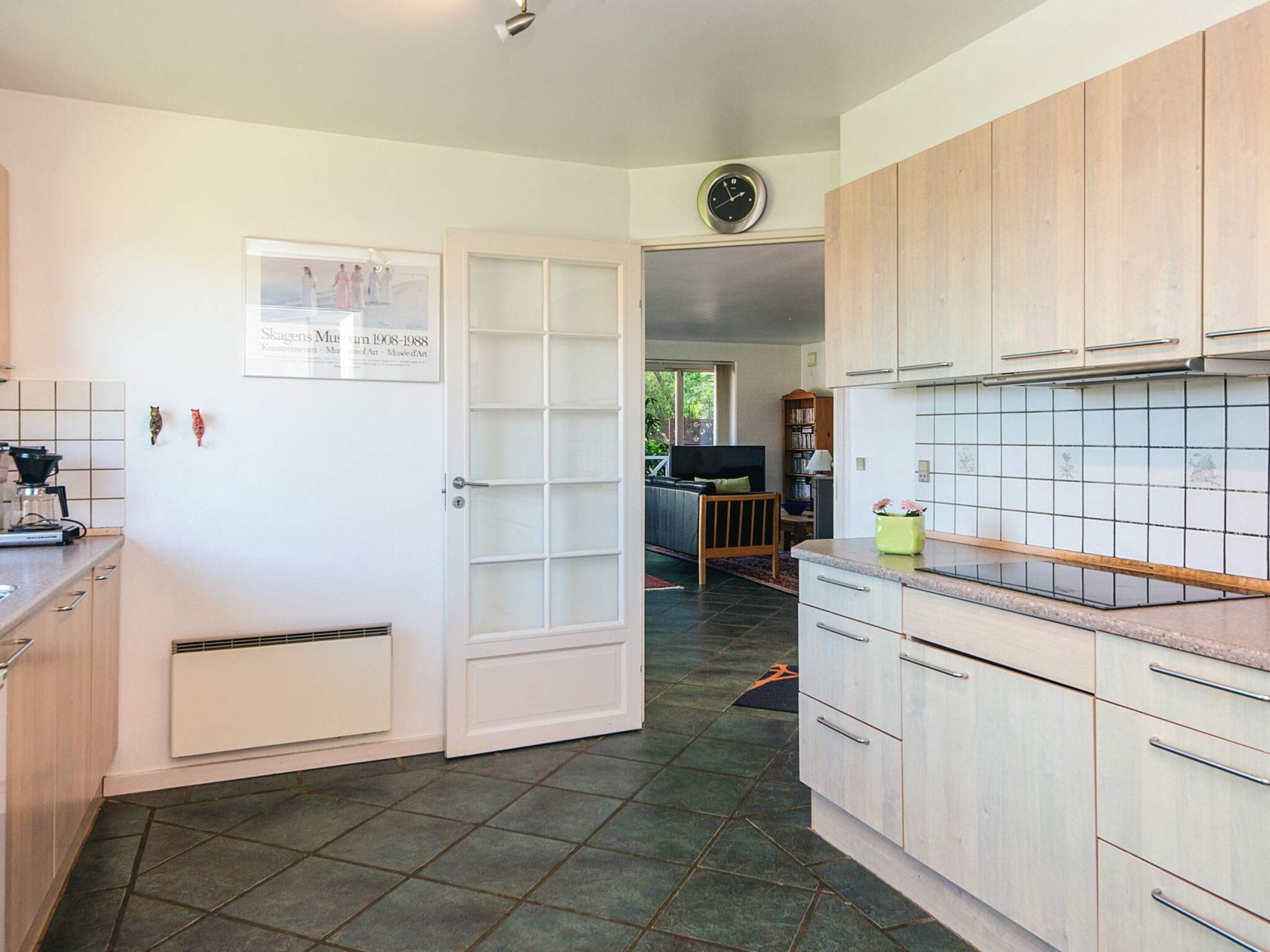 A kitchen with light wood cabinets, a tiled backsplash, a coffee machine, and a framed picture on the wall.