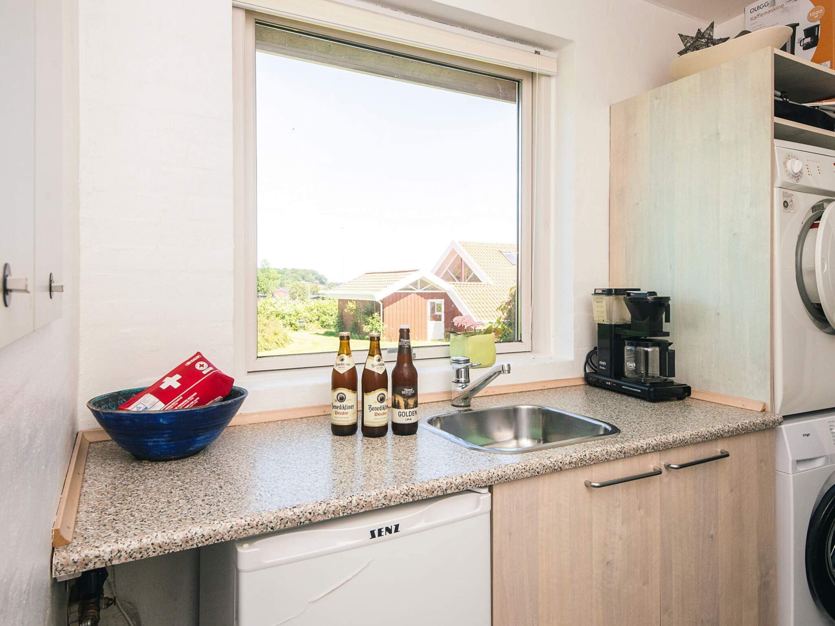 A kitchen with a window, a sink, a coffee machine, and a washing machine.