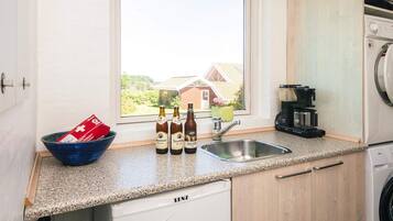 A kitchen with a window, a sink, a coffee machine, and a washing machine.