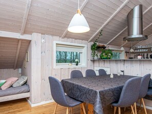 Un interior de cabaña acogedor, con una mesa de comedor, sillas, un sofá, una ventana y una zona de cocina.