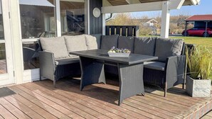 Un patio al aire libre con sofá, mesa y sillas.