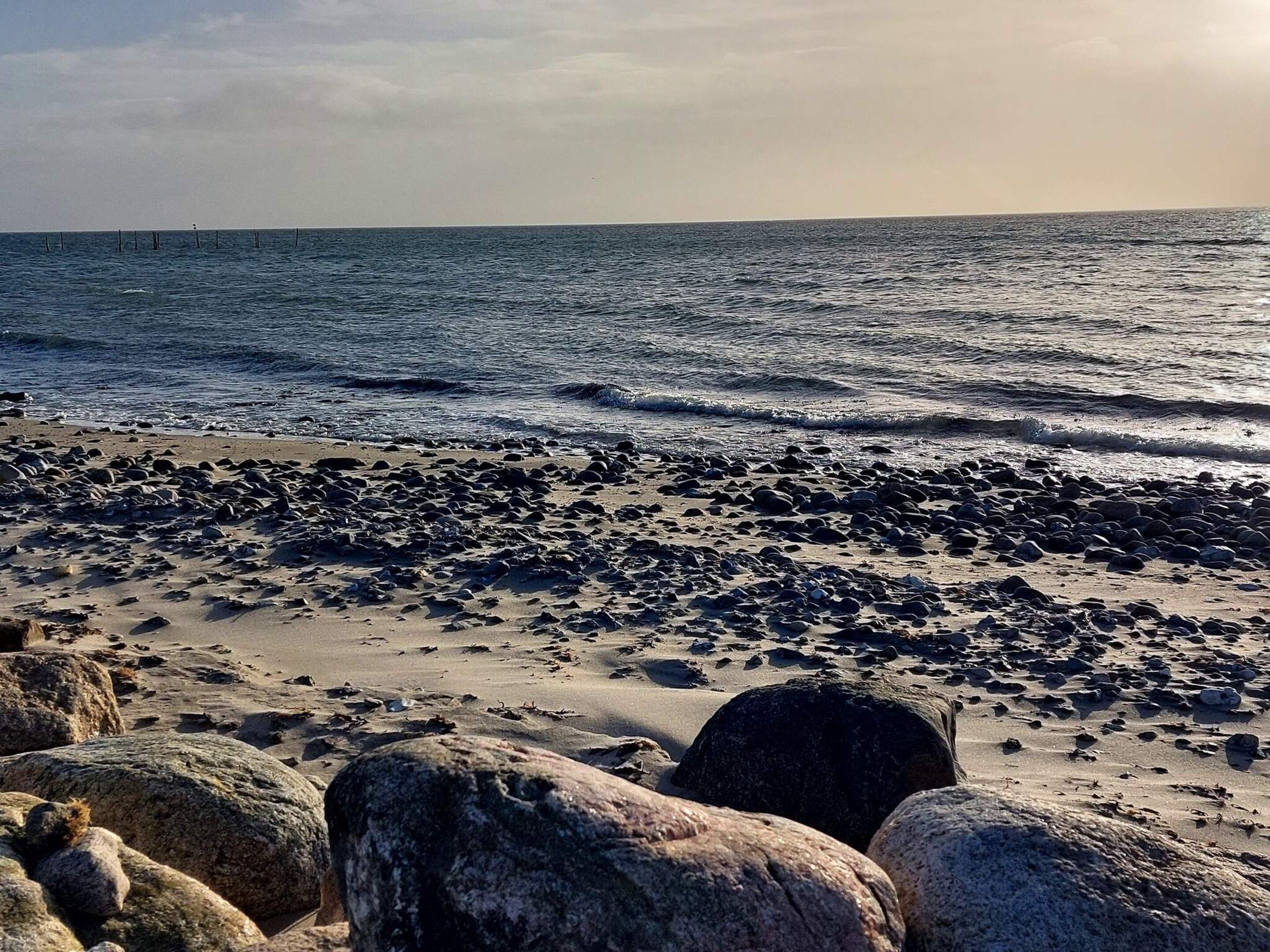 Ein felsiger Strand mit Wellen, einem klaren Himmel und weiter Ferne.