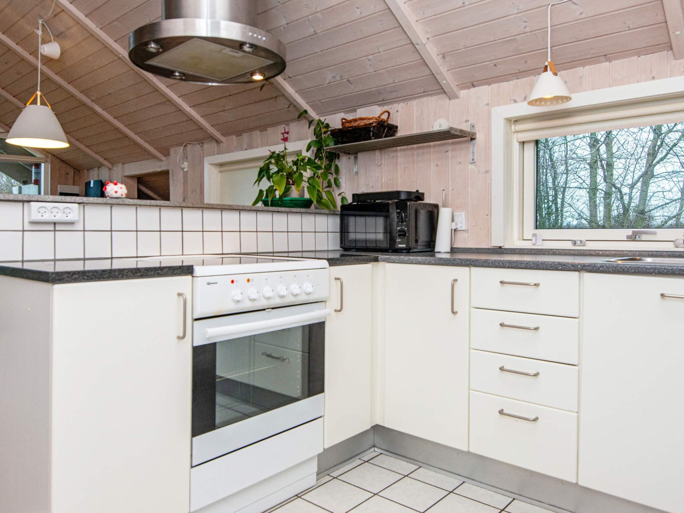 Eine Küche mit Herd, Backofen, Mikrowelle und weißen Schränken.