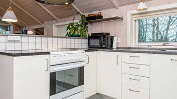 Eine Küche mit Herd, Backofen, Mikrowelle und weißen Schränken.