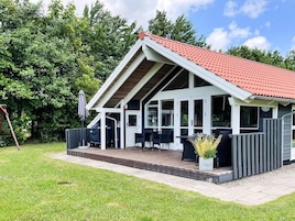A covered outdoor patio with a dining area, a covered entryway, and a small garden area with a potted plant.