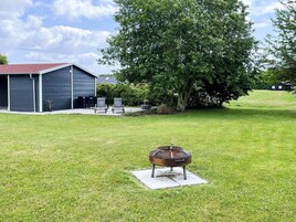 A backyard with a barbecue grill, a shed, and a tree.