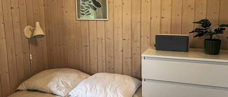 Une chambre à coucher avec un lit, une table de chevet avec une lampe, un tableau encadré et une plante en pot.