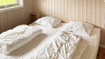 Ein Schlafzimmer mit einer Holzvertäfelung, einem Fenster und einem Nachttisch mit Lampe.