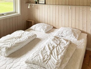 A bedroom with a wooden paneled wall, a window, and a bedside table with a lamp. - 6 Person Holiday Home in Sydals (Sydals)