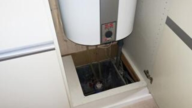 A water heater in a utility room with exposed pipes and a vent. - 5 Star Holiday Home in Harboore (Harboore)