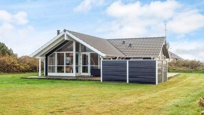 A modern house with a large glass windowed porch, a sloped roof, and a fenced yard.