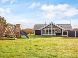 A residential property with a play area, a covered patio, and a house with a tiled roof.