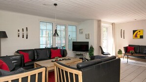 A modern living room with a sofa set, a coffee table, and a TV. - Luxurious Cabin With Pool in Ringkøbing (Ringkobing)