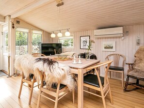 A wooden dining area with a table, chairs, and a television.