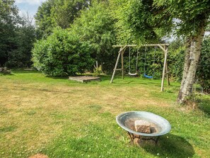 Un jardin avec une balançoire, une mangeoire à oiseaux et un foyer.