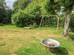 A backyard with a swing set, a bird feeder, and a fire pit. - 4 Star Holiday Home in Lokken (Lokken)