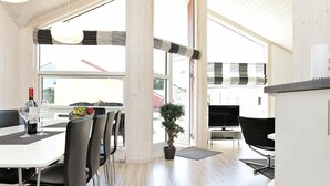 A modern dining area with a white table, black chairs, and a potted plant.