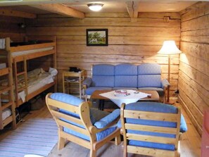 Ein Ferienhausinnenraum mit Etagenbetten, einer Couch, einem Tisch und einer Lampe.