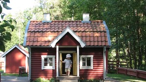 A red wooden house with a pitched roof, a front door, and a small porch. - 8 Person Holiday Home in Vimmerby (Vimmerby)