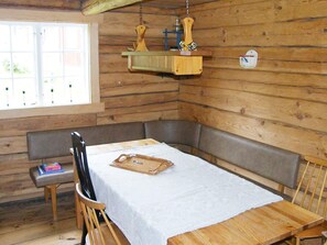 L’intérieur d’un chalet en bois, avec une table à manger, des bancs et un luminaire suspendu.