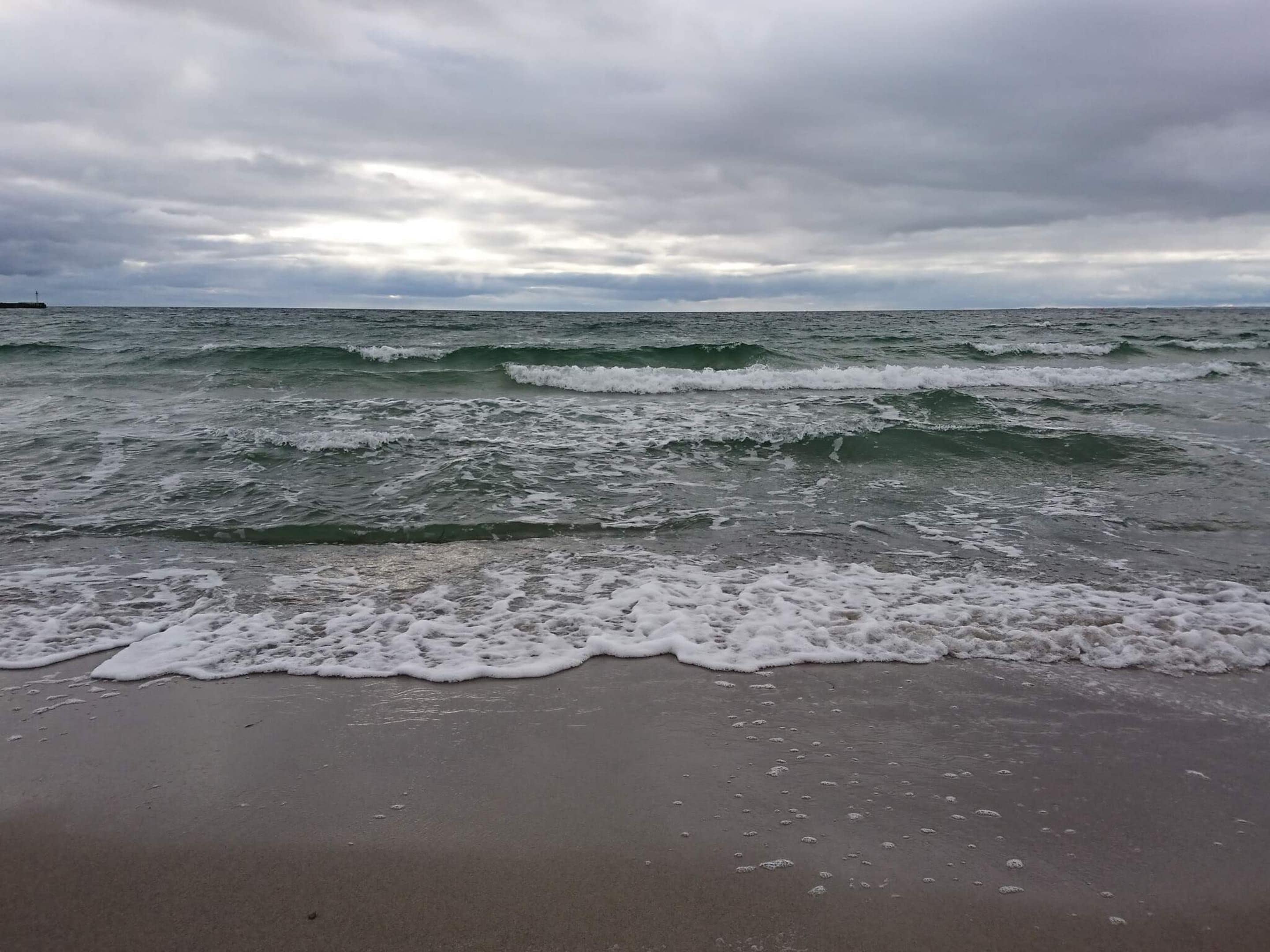 Una playa con olas que se acercan a la orilla bajo un cielo nublado.