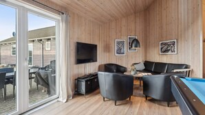 A cozy room with a wooden ceiling, a flat-screen TV mounted on the wall, a pool table, and a leather sofa. - 5 Star Holiday Home in Bagenkop (Sydlangeland)