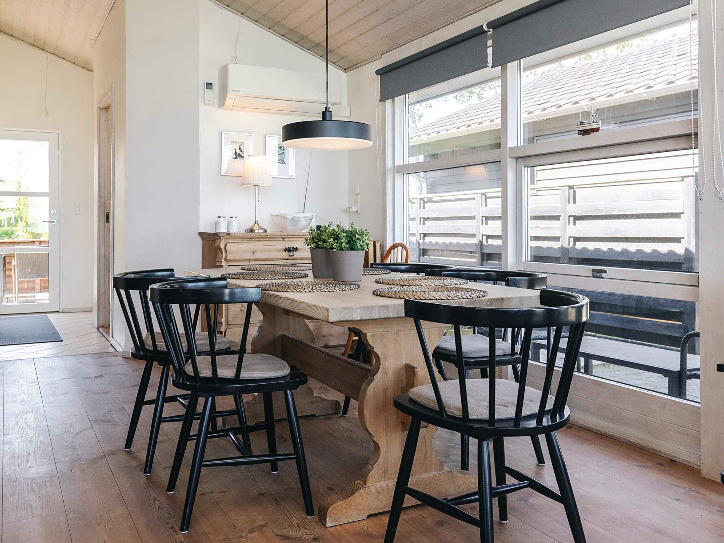 Une cuisine moderne dotée d’un îlot central, de tabourets de bar noirs et d’une grande fenêtre offrant une vue dégagée.