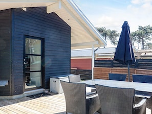 A covered patio with a table and chairs, a sliding glass door, and a blue umbrella.