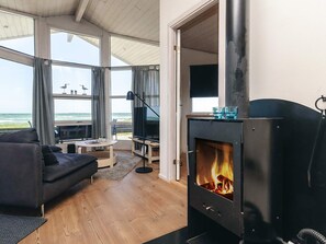 A cozy living room with a fireplace, a sofa, a coffee table, and a view of the ocean. - Luring Holiday Home in Poljana With Sea Nearby (Otterup)