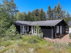 A rustic cabin with a porch, surrounded by dense forest. - 6 Person Holiday Home in Albaek (Aalbaek)