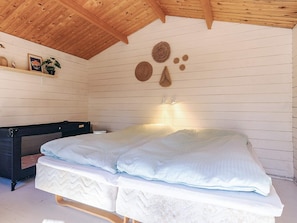 A bedroom with a bed, a desk, and a ceiling with wooden beams. - 6 Person Holiday Home in Albaek (Aalbaek)