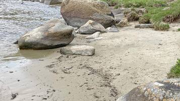 A natural landscape with a river, large rocks, and grassy areas.