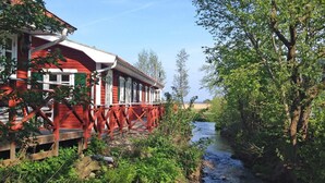 En rød træbygning med balkon, der kigger ud over en flod.
