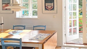 A dining area with a wooden table, blue chairs, and a window with a view of greenery. - Holiday Home in SÃ¶lvesborg (Sölvesborg)