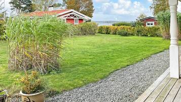 A well-maintained lawn with a gravel path leading to a wooden deck.