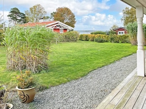 Un césped bien cuidado con un sendero de grava que conduce a una terraza de madera.